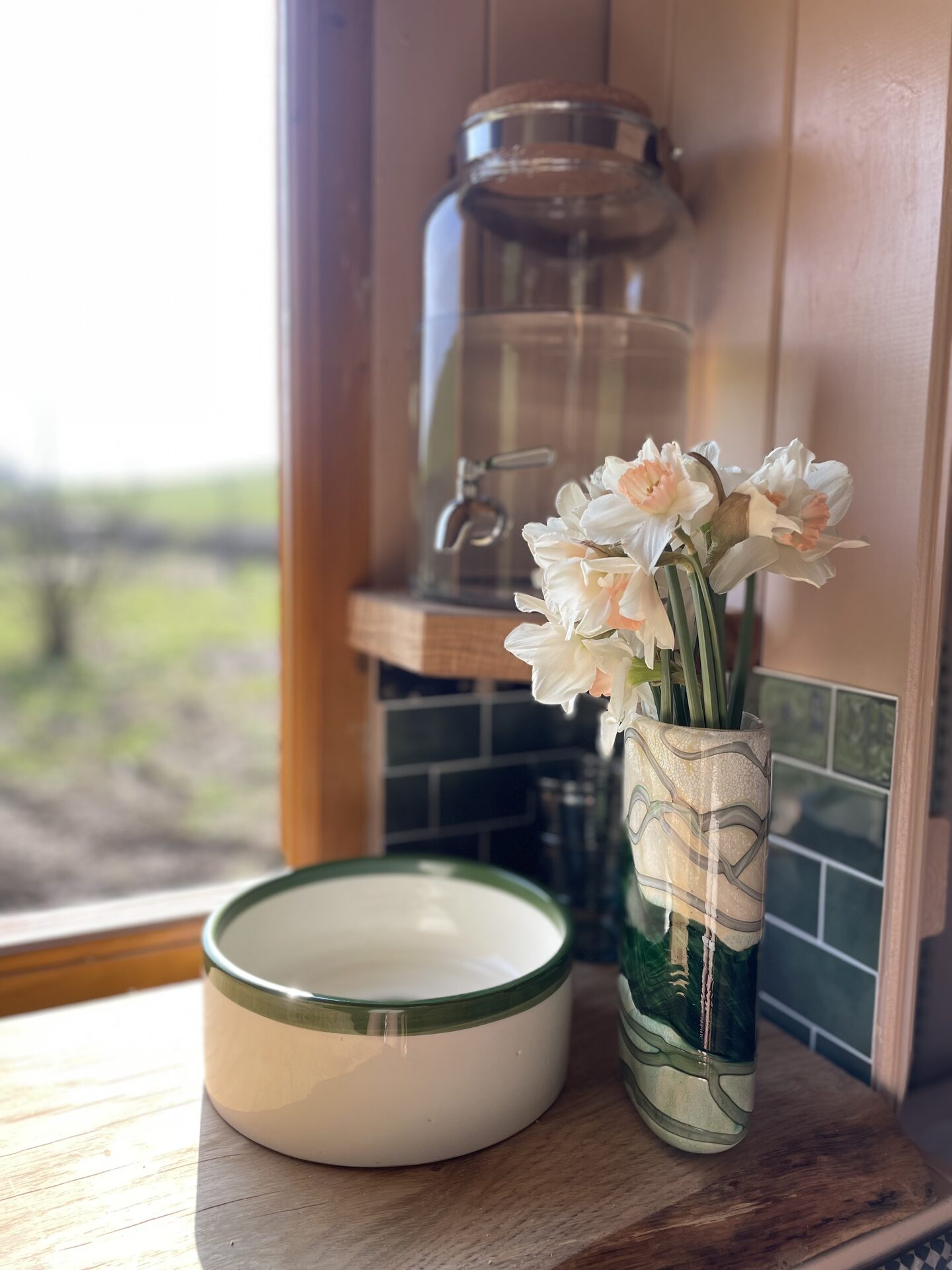 Fresh daffodils, enamel bowl and glass water dispenser on the hut worktop